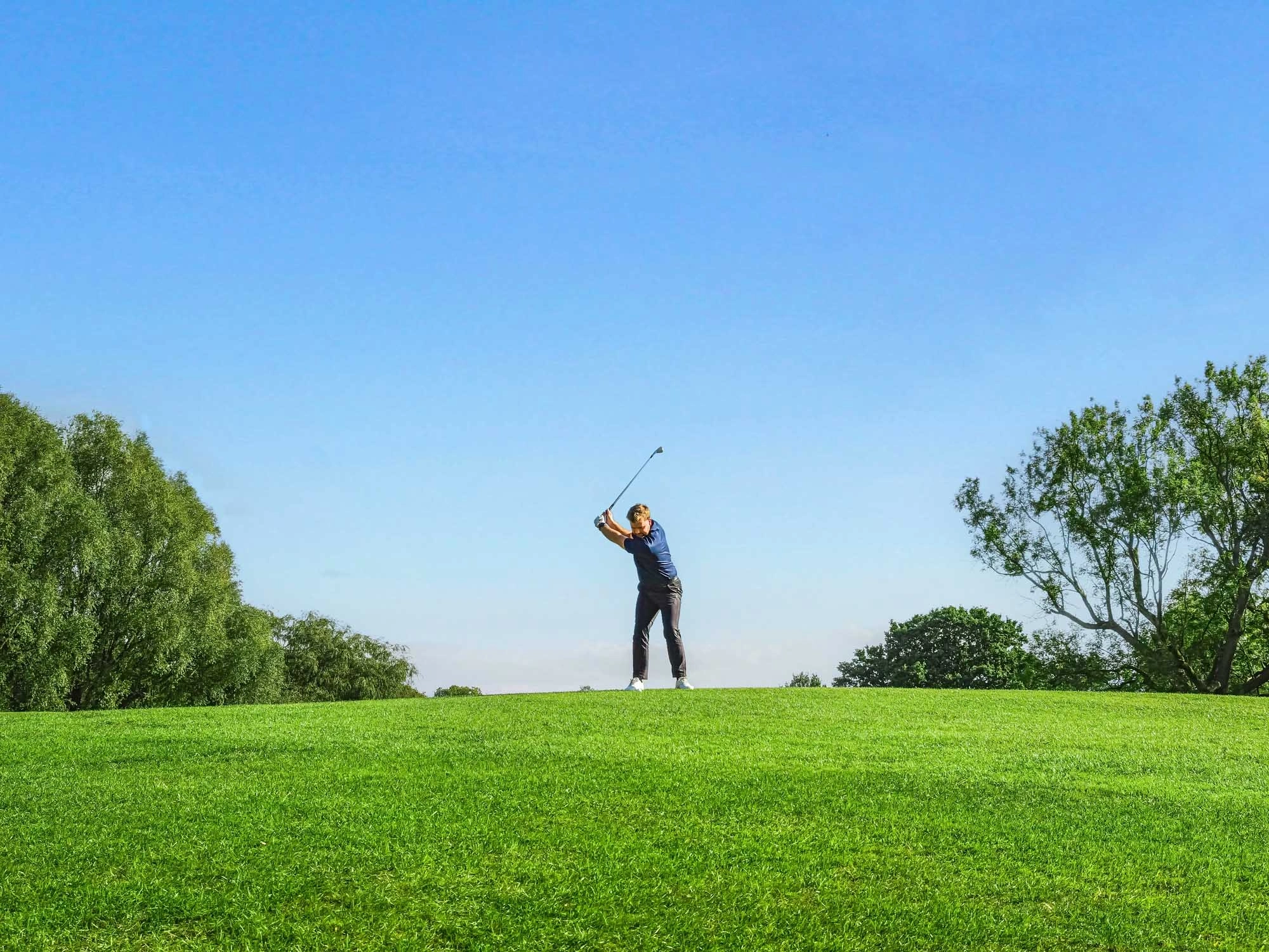 Male swinging club on golf course