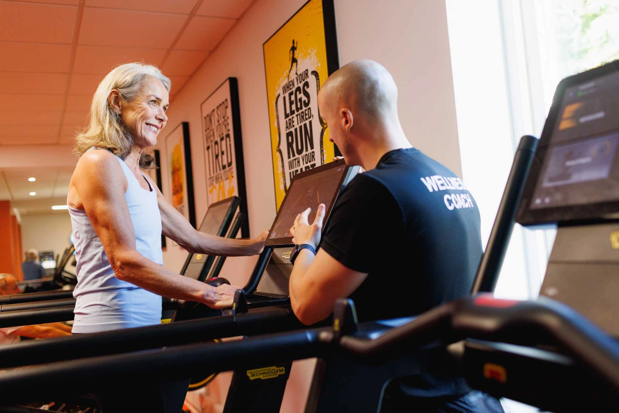 lady on running machine being guided by a personal trainer