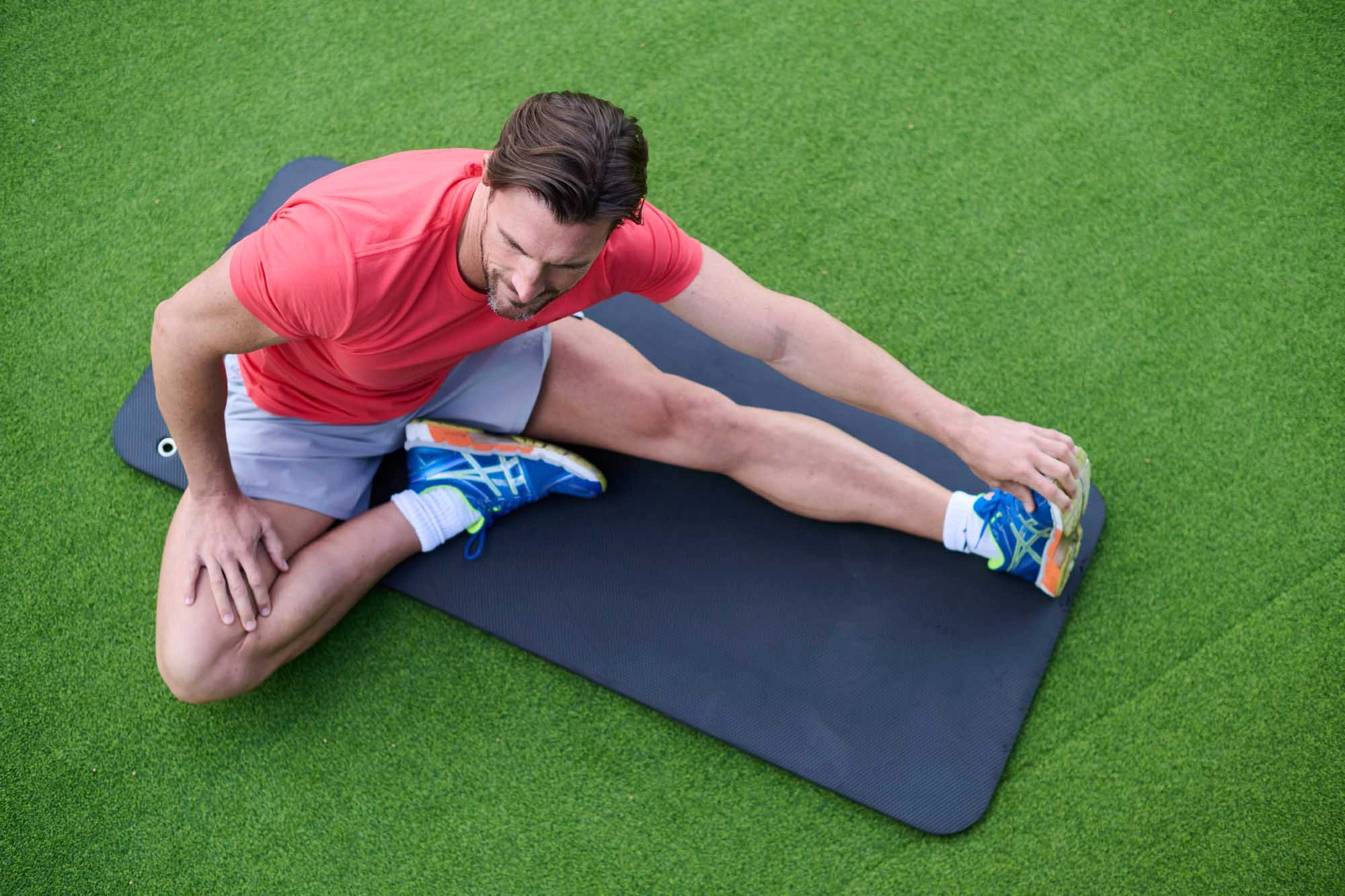 man stretching outside on mat