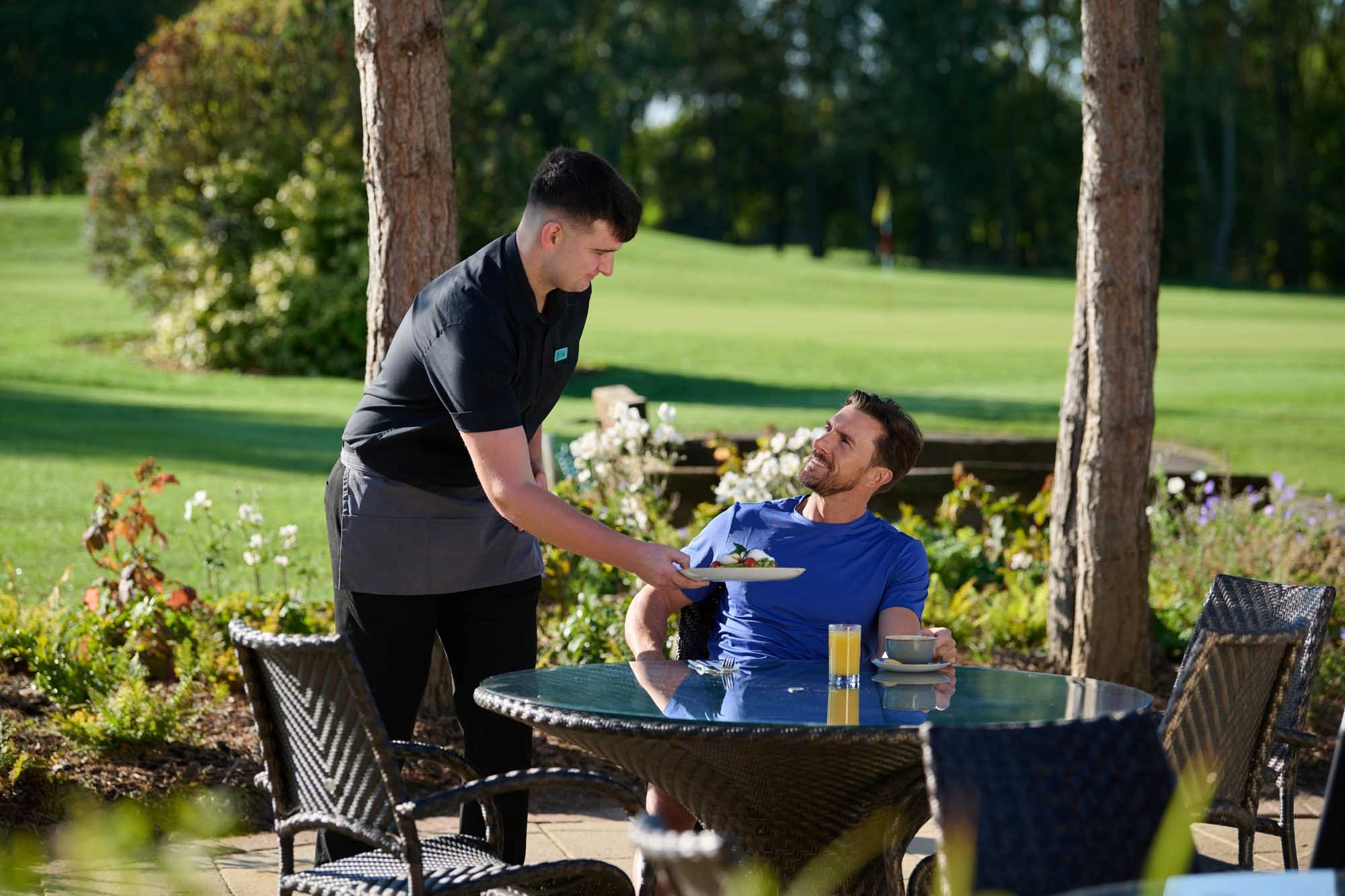 waiter serving man breakfast outside